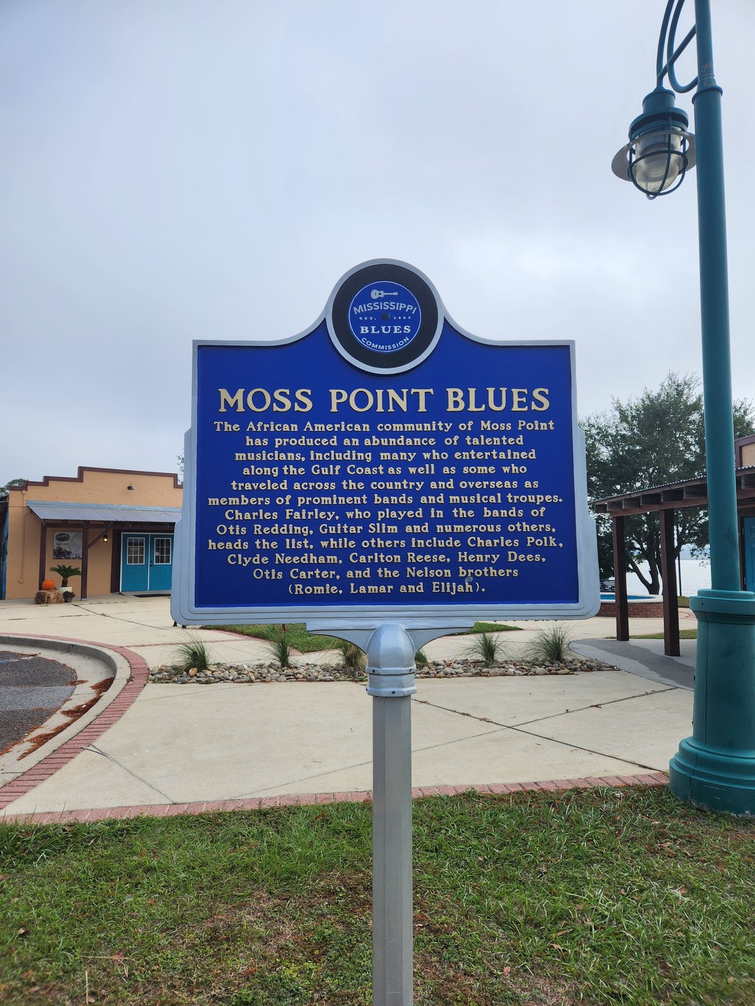 The Mississippi Blues Trail marker titled Moss Point Blues standing on a sidewalk in downtown Moss Point.