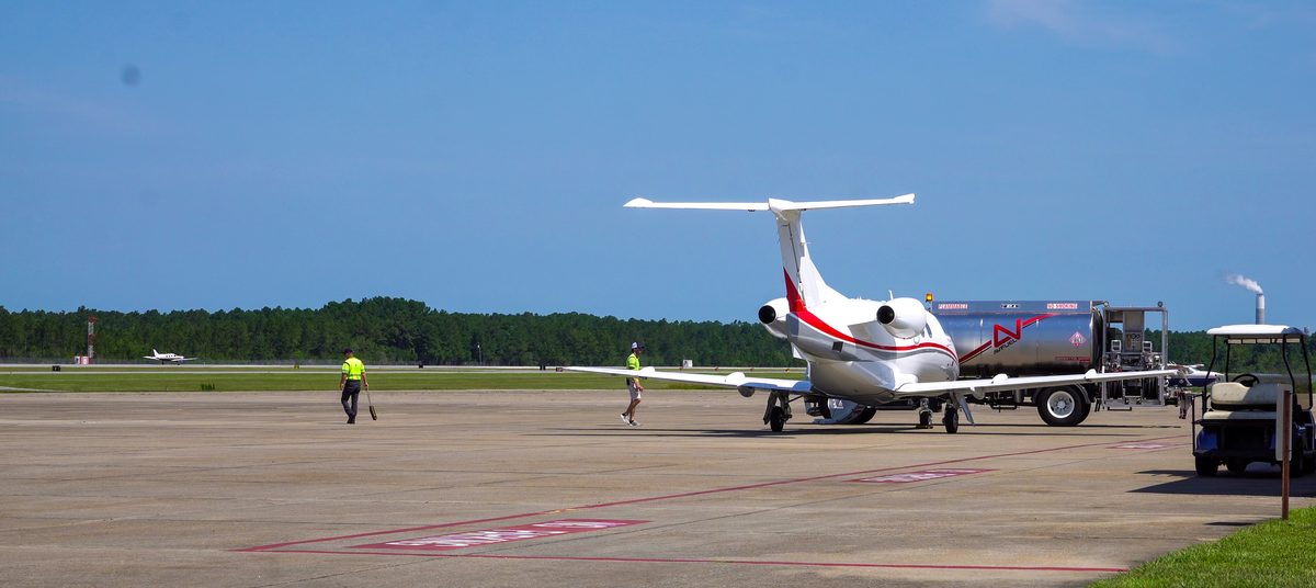 A business jet on the apron at Trent Lott International Airport in Moss Point, with the runway beyond.