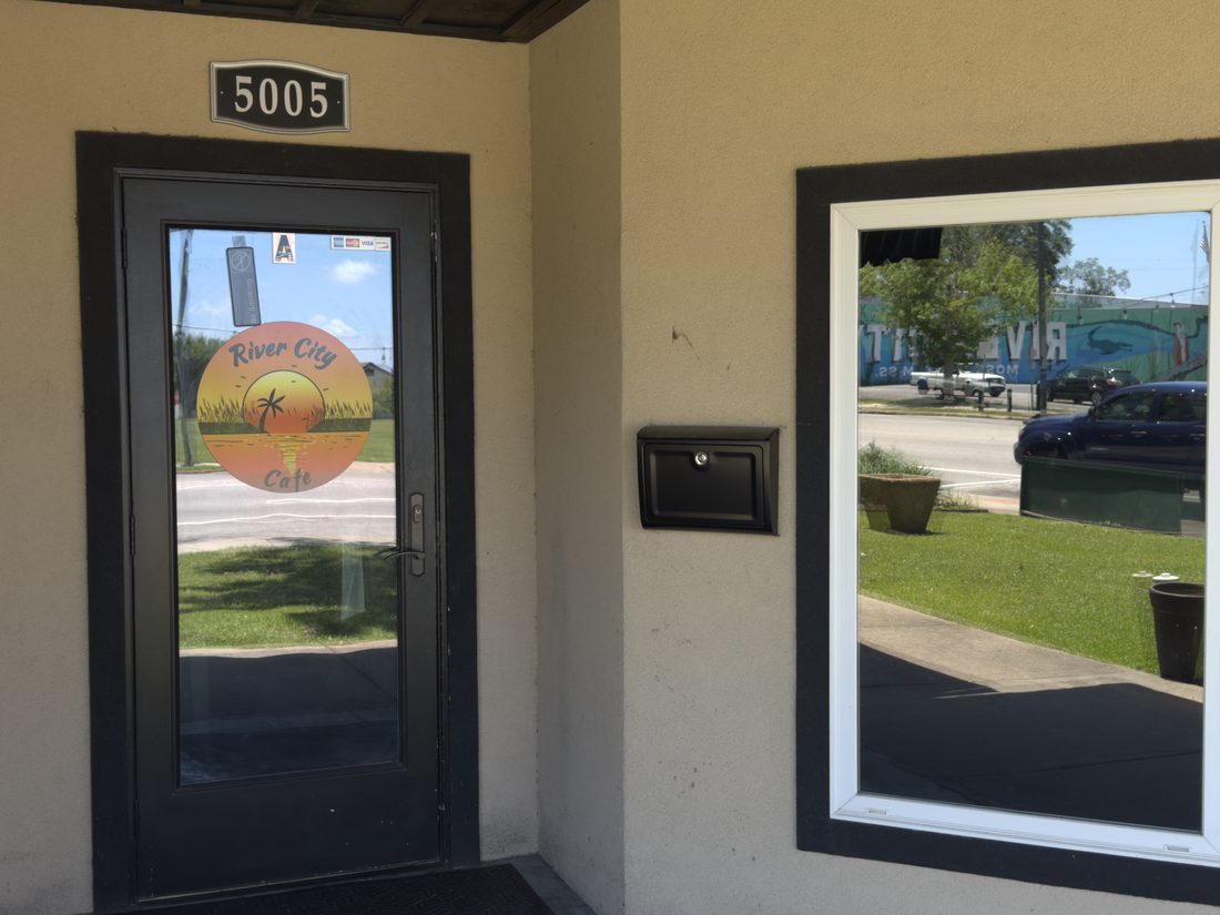 The River City Cafe storefront door with its sunset and palm logo downtown.