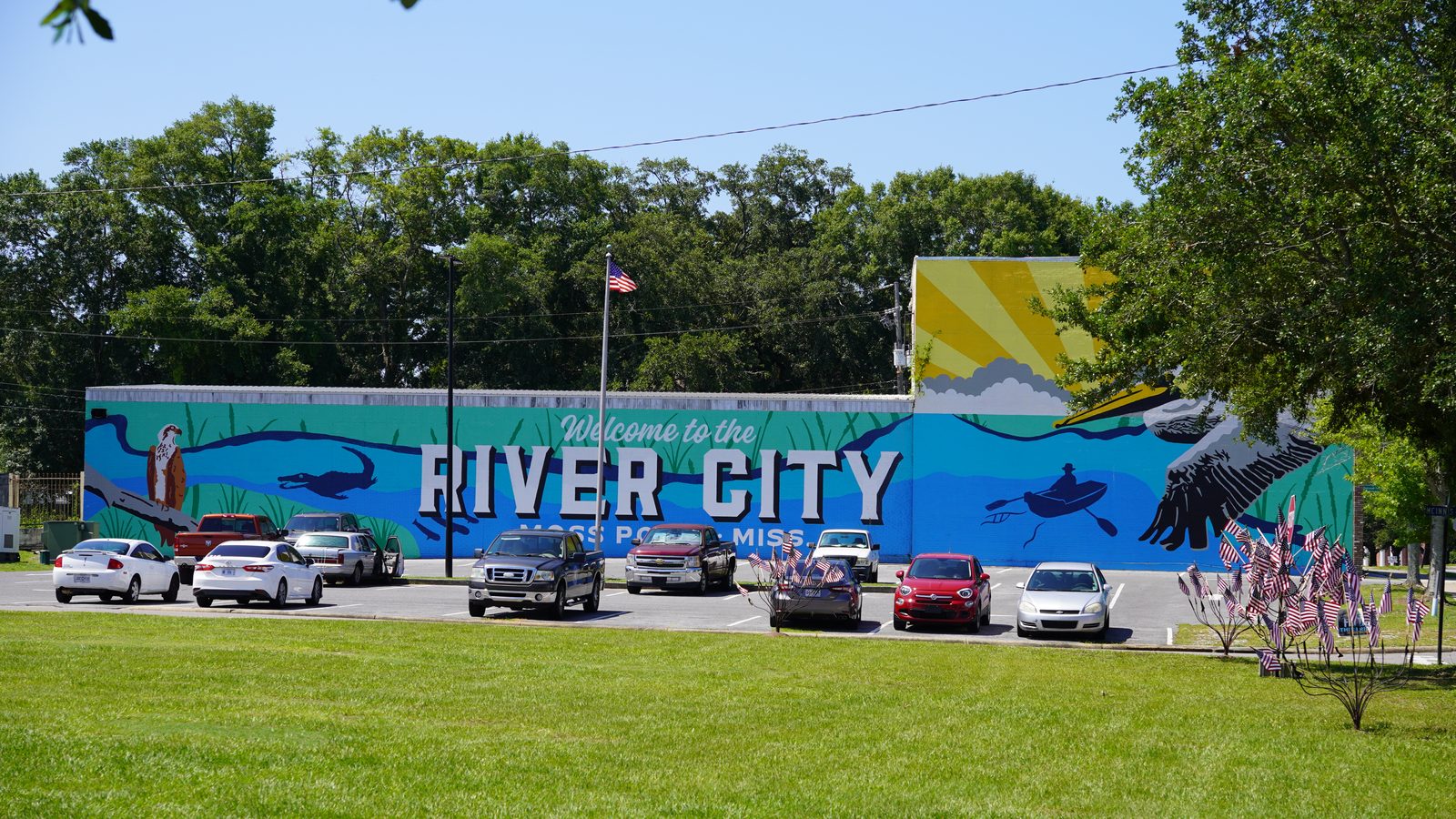A large mural reading Welcome to the River City, Moss Point Mississippi, with herons and a kayaker.