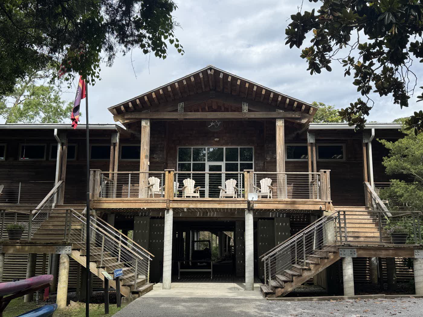 The Pascagoula River Audubon Center in Moss Point, a raised cypress timber building with a gabled porch, twin staircases, and a heron emblem on the gable.