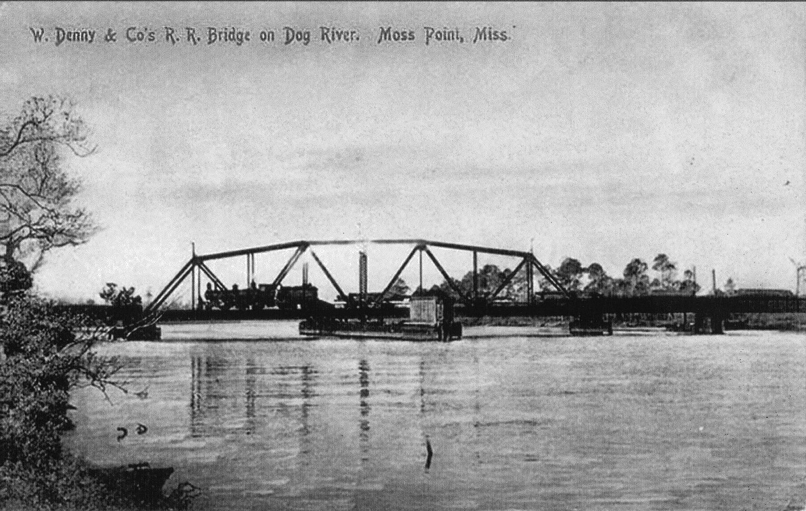 An early steel railroad swing bridge crosses the river at Moss Point.