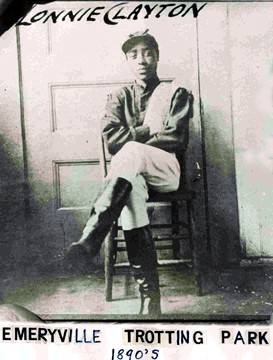 The young African American jockey Lonnie Clayton seated in his racing silks and tall riding boots in the 1890s.