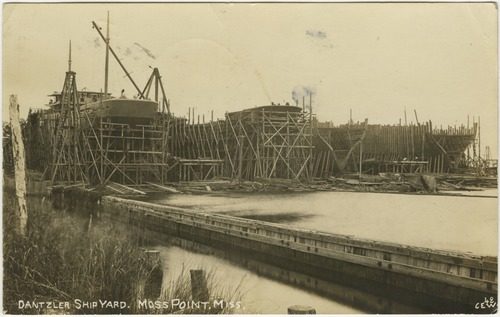 Wooden ships under construction on the ways at the Dantzler shipyard in Moss Point, photographed from across the water in the early 1900s.
