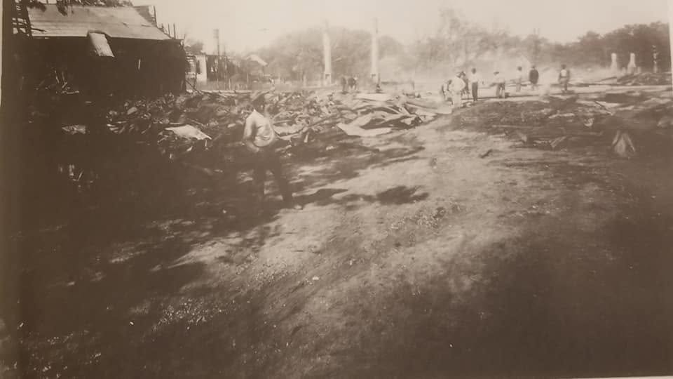 A man in light clothes walks through the charred debris of the Moss Point business district after the 1923 fire.