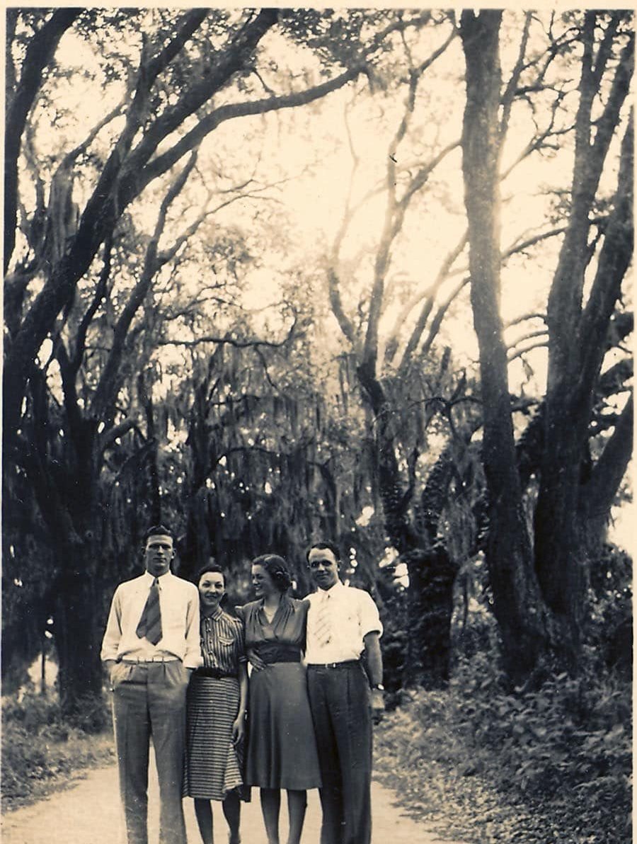 Two couples stand on a tree lined lane under a tunnel of live oaks in Moss Point in 1939.