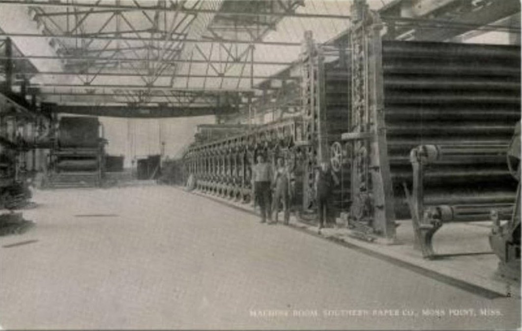 Workers stand beside the long paper making machine inside the machine room of the Southern Paper Company mill in Moss Point.