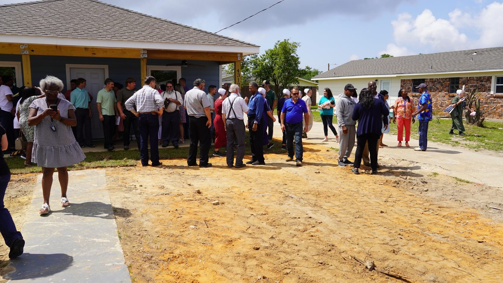 A newly built home and a community gathering on a cleared lot in Moss Point after the 2023 tornado.