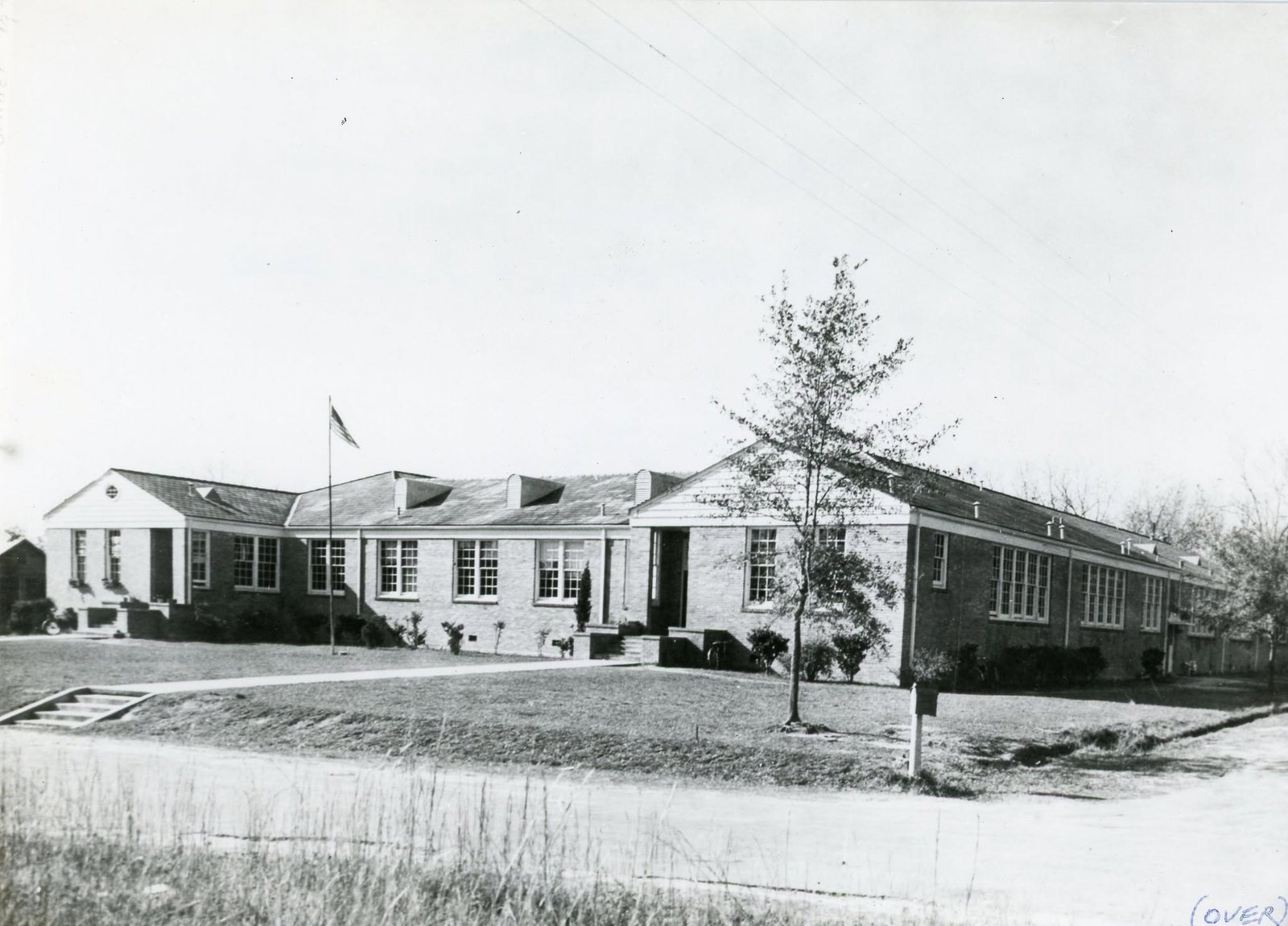 The long one story brick Magnolia Elementary School building with a flag pole out front, built 1932.