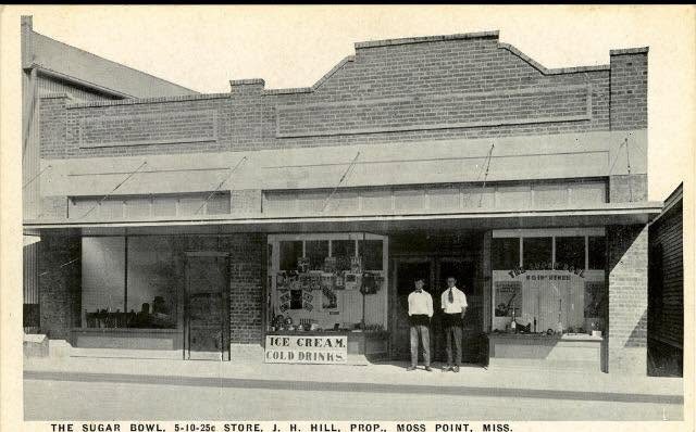 Two men stand in the doorway of the Sugar Bowl five ten and twenty five cent store with ice cream and cold drinks signs.