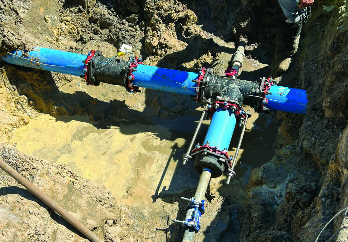 New blue PVC water main and bolted fittings joined together in the open trench during the Kimberly Drive water line replacement in Moss Point.