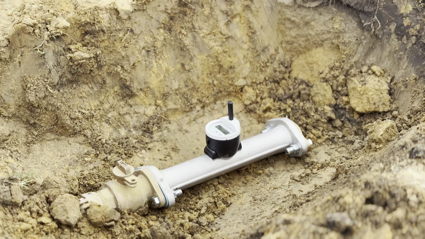 A new water meter with a digital readout and radio transmitter resting in a freshly dug trench during installation in Moss Point.