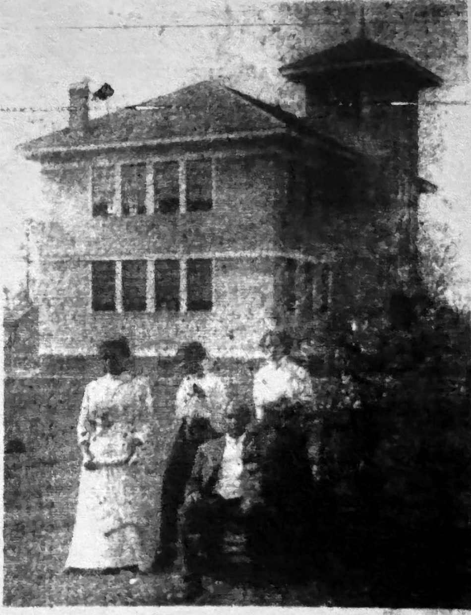 Magnolia Academy in 1910, a schoolhouse with a square tower, teachers in long white dresses gathered on the grounds in front.
