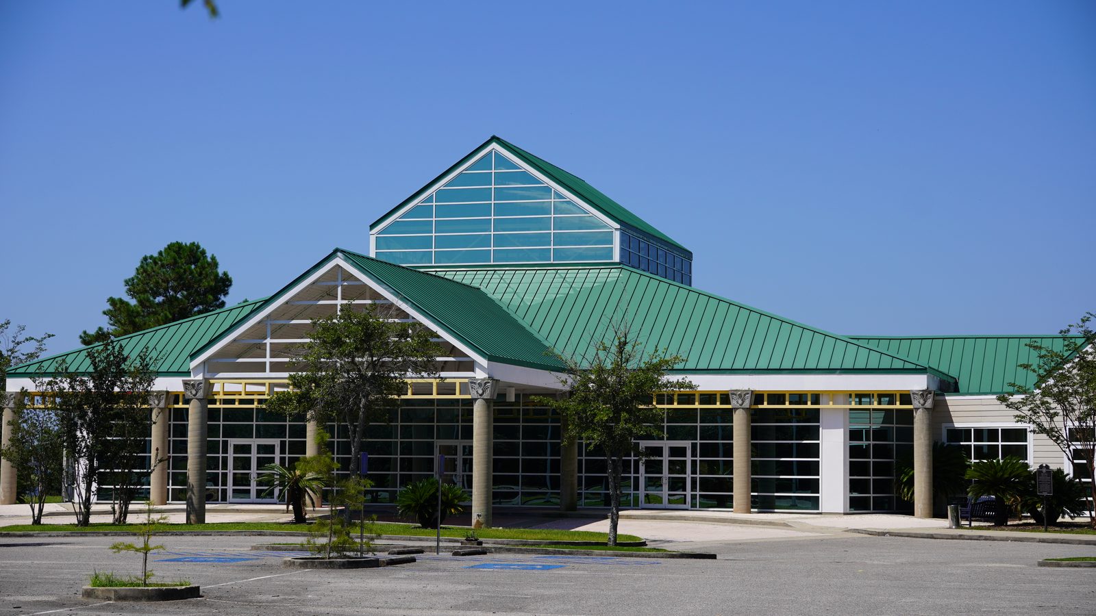 The green-roofed Pelican Landing event building, three-quarter view of the grand entrance and glass gable