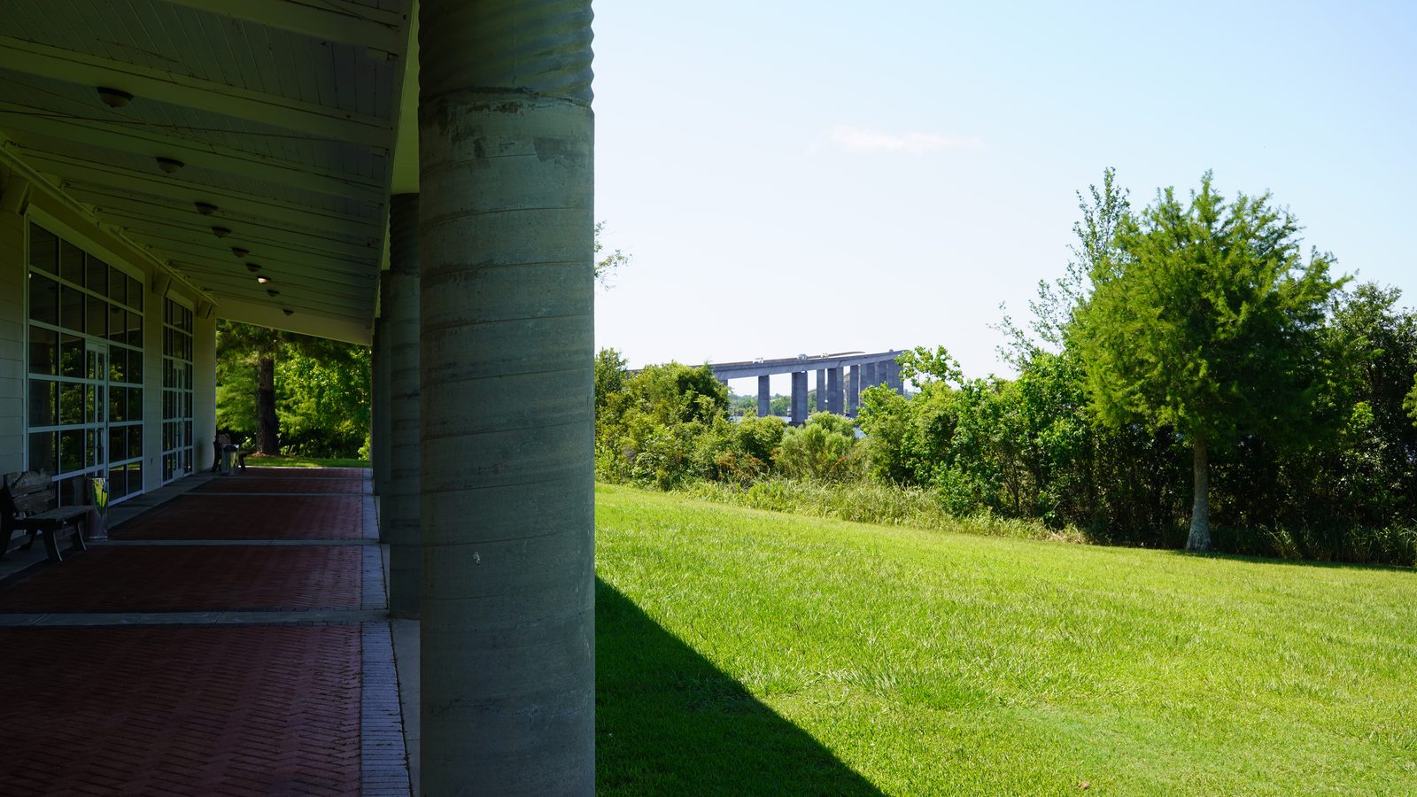The covered veranda of the Pelican Landing event building opening onto the lawn and the Escatawpa River