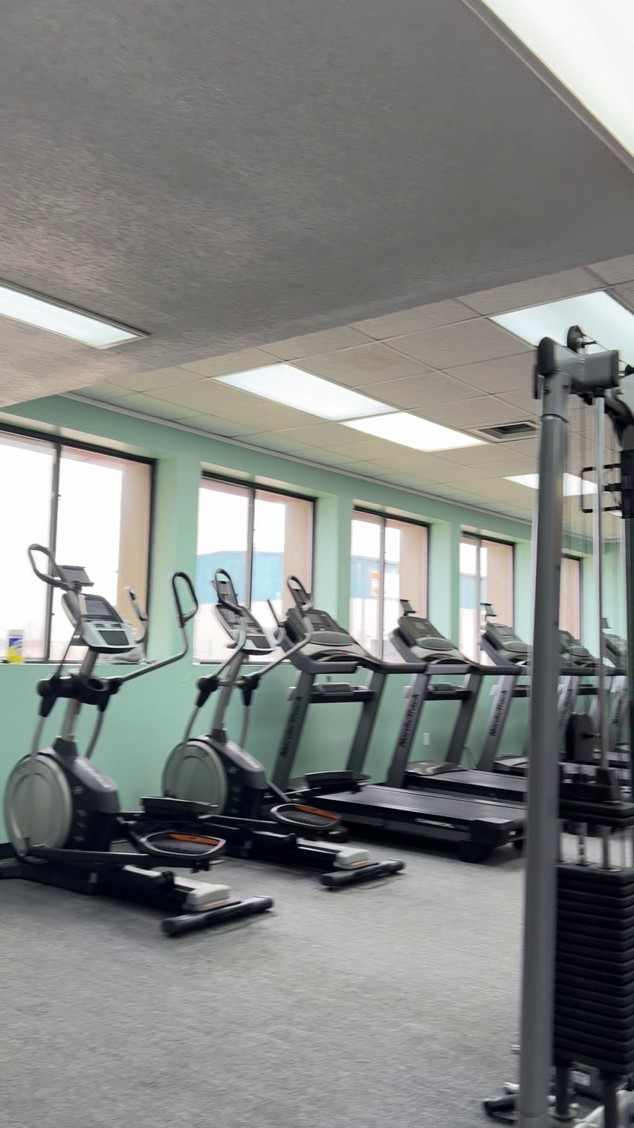Inside the River City Fitness Center, treadmills and cardio equipment by the windows.