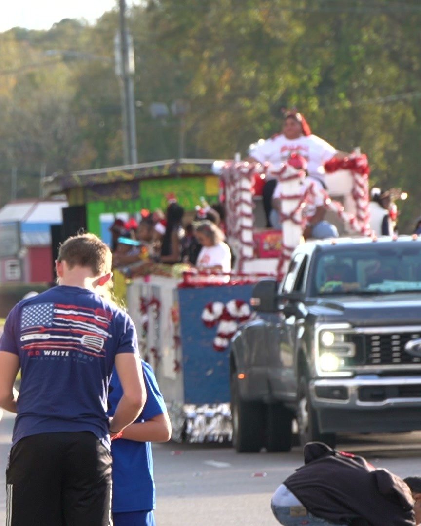 A candy cane float rolls down Main Street during last year's Christmas by the River Land Parade as a boy watches from the curb.