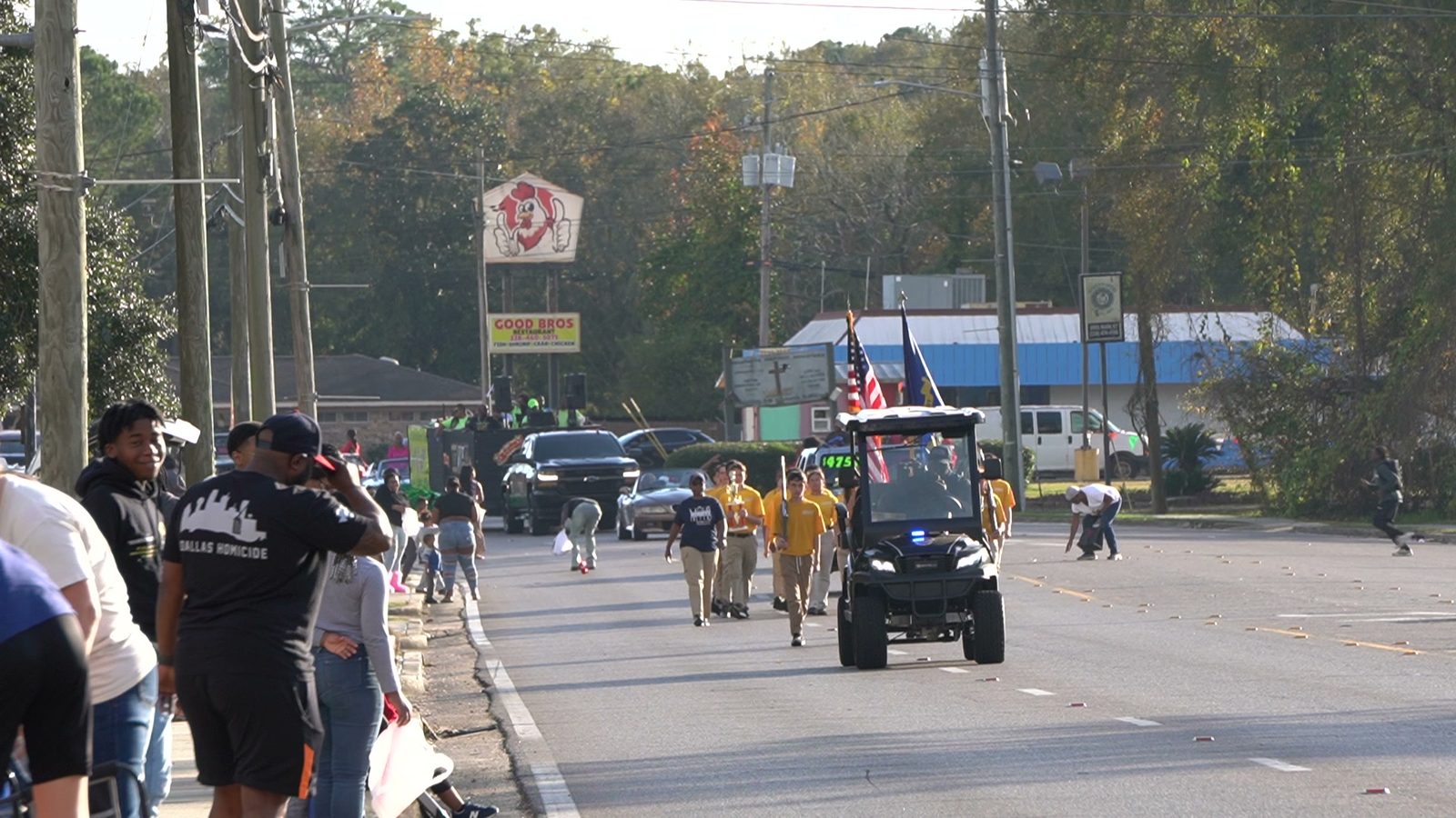 Enter the Christmas Parade: families line Main Street as a marching group in gold shirts walks beside a golf cart flying the American flag in last year's Land Parade in Moss Point